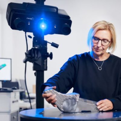 A woman performs a 3D metrology scan of a metal part