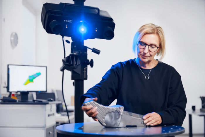 A woman performs a 3D metrology scan of a metal part